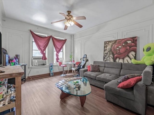 living room with baseboards, ceiling fan, cooling unit, and wood finished floors
