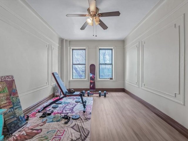 workout room with baseboards, a ceiling fan, and light wood finished floors