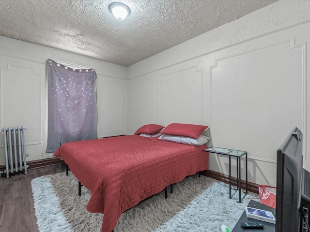 bedroom featuring radiator heating unit, a textured ceiling, and wood finished floors