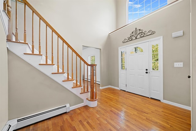 entrance foyer with a towering ceiling, wood finished floors, baseboards, a baseboard heating unit, and a baseboard radiator