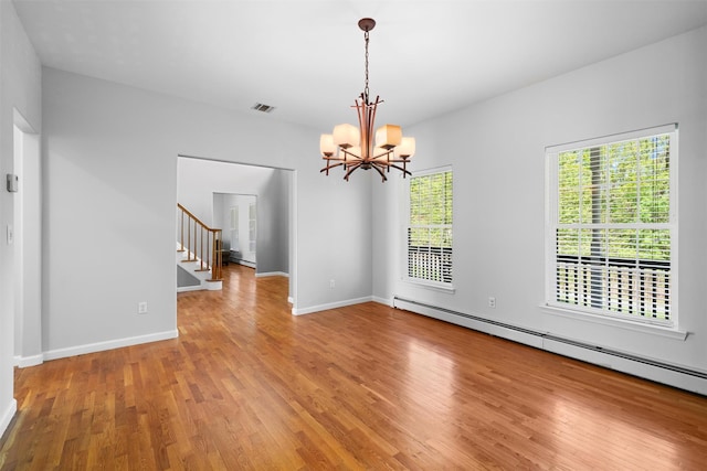 empty room featuring visible vents, stairway, a chandelier, a baseboard radiator, and light wood finished floors
