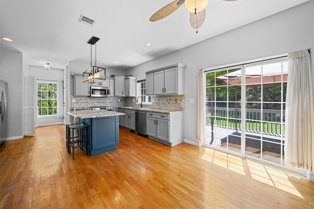 kitchen with stainless steel appliances, gray cabinetry, a sink, and visible vents