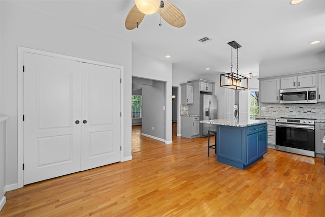 kitchen with ceiling fan, light wood finished floors, a breakfast bar area, stainless steel appliances, and tasteful backsplash