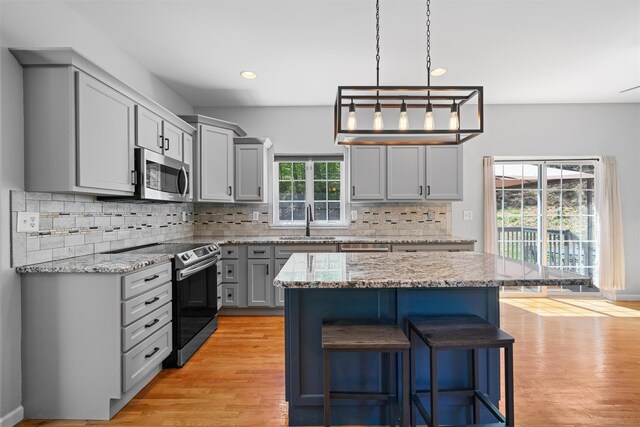 kitchen with gray cabinets, a breakfast bar area, a sink, stainless steel appliances, and recessed lighting