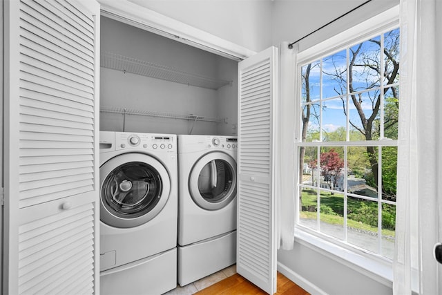 laundry area with laundry area, light wood finished floors, washing machine and dryer, and a wealth of natural light