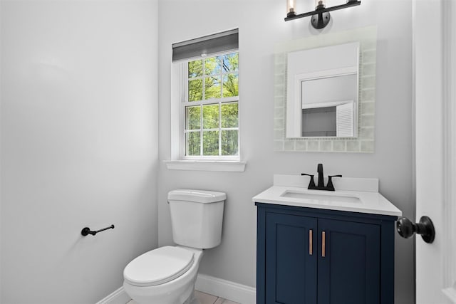 bathroom featuring toilet, baseboards, and vanity