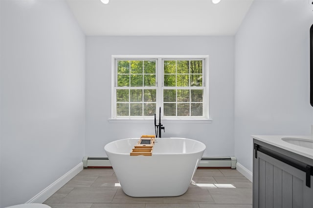 full bath with baseboards, a freestanding tub, baseboard heating, and vanity