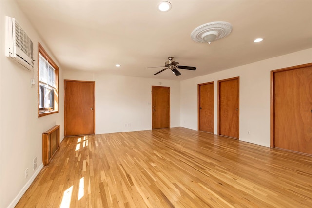 unfurnished living room with ceiling fan, light wood finished floors, recessed lighting, baseboards, and a wall unit AC