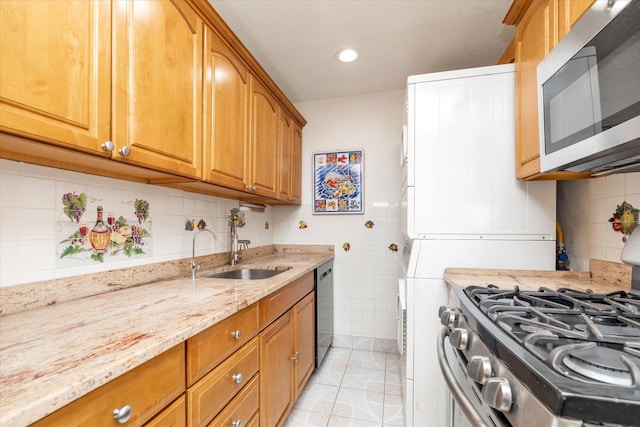kitchen with tile walls, light stone countertops, a sink, stainless steel appliances, and light tile patterned flooring