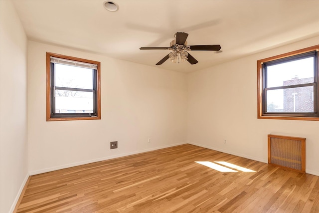 unfurnished room featuring baseboards, light wood finished floors, ceiling fan, and radiator heating unit