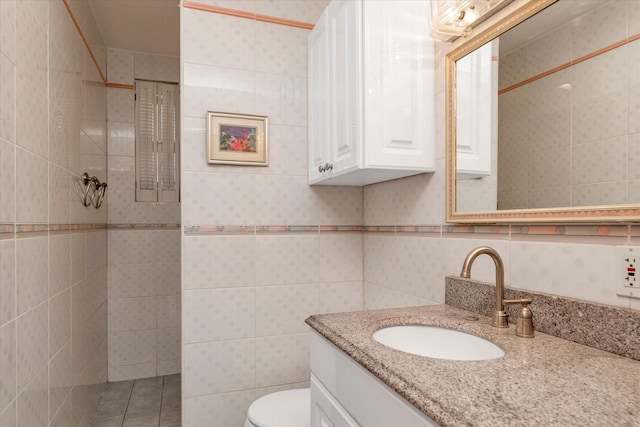 full bath with tile walls, a tile shower, vanity, and toilet