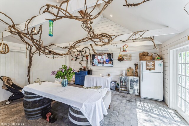 dining room with high vaulted ceiling and wood walls