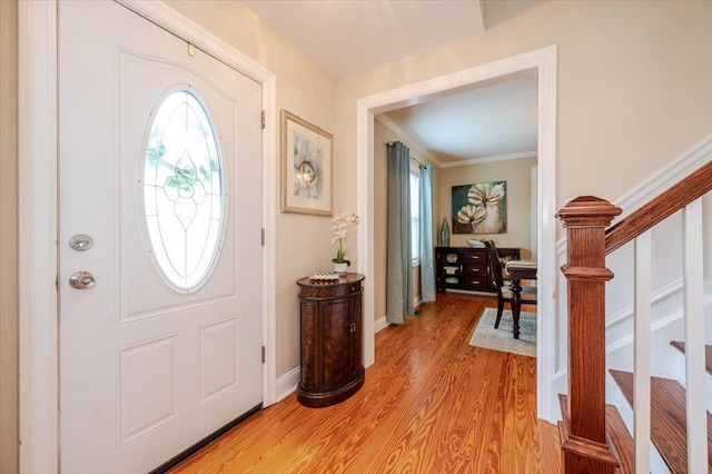entrance foyer with crown molding, a healthy amount of sunlight, stairway, and light wood-style floors