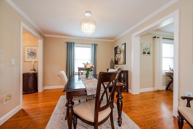 dining space with an inviting chandelier, baseboards, ornamental molding, and light wood-style flooring