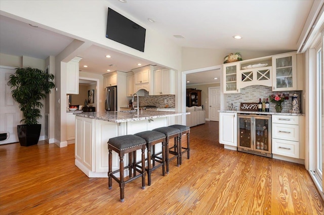 kitchen with beverage cooler, a breakfast bar, backsplash, and fridge