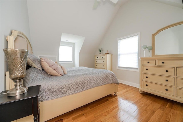 bedroom featuring baseboards, multiple windows, lofted ceiling, and light wood-style floors