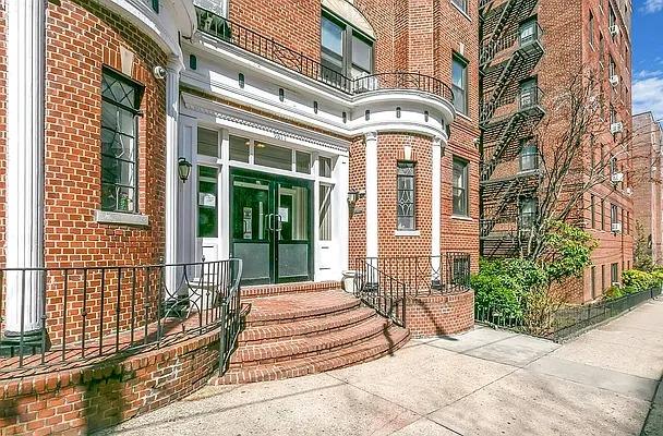 entrance to property featuring a balcony and brick siding