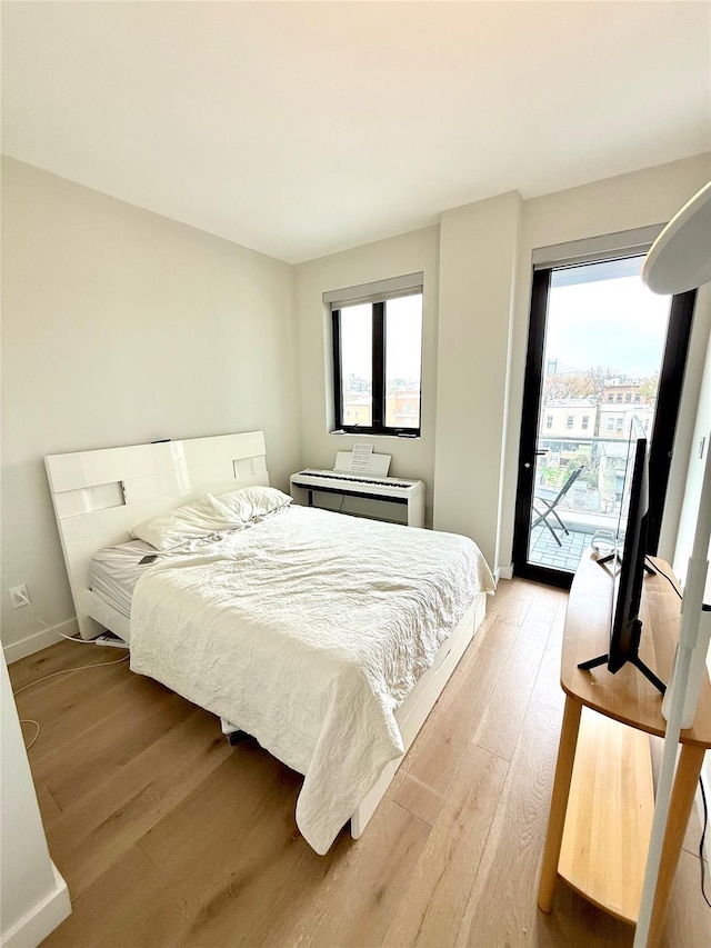 14-33 31st Ave Unit 4H, Astoria, NY 11106 - bedroom featuring baseboards, access to exterior, multiple windows, and light wood-type flooring