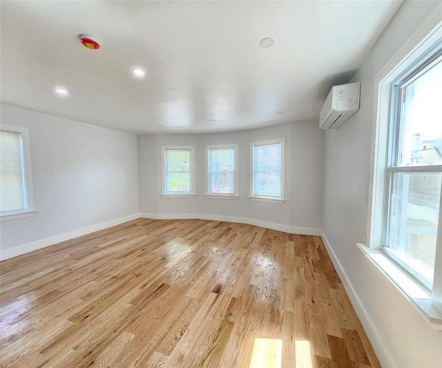 interior space with recessed lighting, baseboards, a wall mounted AC, and light wood-type flooring