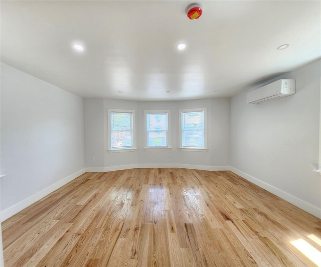 spare room with light wood-style floors, baseboards, a wall mounted AC, and recessed lighting