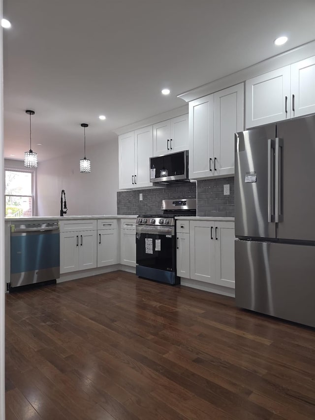 217 E 86th St, Brooklyn, NY 11236 - kitchen with appliances with stainless steel finishes, dark wood-type flooring, tasteful backsplash, white cabinetry, and pendant lighting