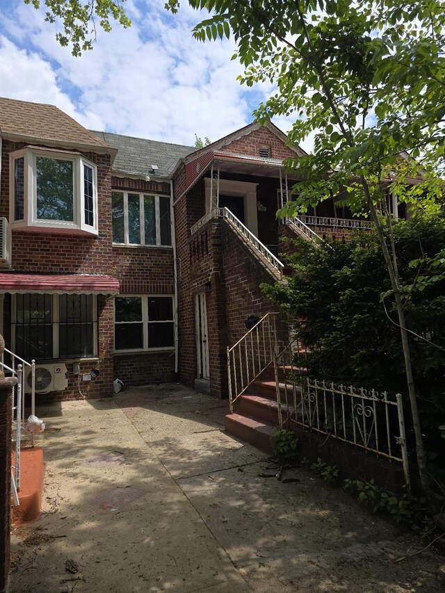 217 E 86th St, Brooklyn, NY 11236 - back of property featuring brick siding, a shingled roof, and a patio
