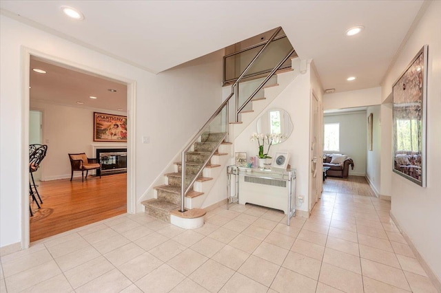 stairs featuring recessed lighting, tile patterned flooring, a glass covered fireplace, and radiator heating unit