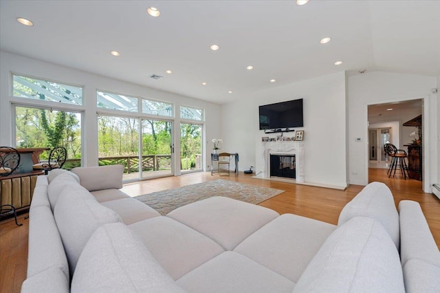 living area with recessed lighting, visible vents, a high end fireplace, vaulted ceiling, and light wood-style floors
