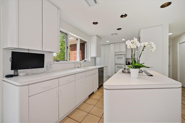 kitchen featuring a center island, a sink, white cabinetry, visible vents, and white appliances