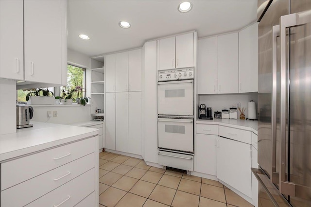 kitchen with a warming drawer, light countertops, stainless steel fridge, and white double oven