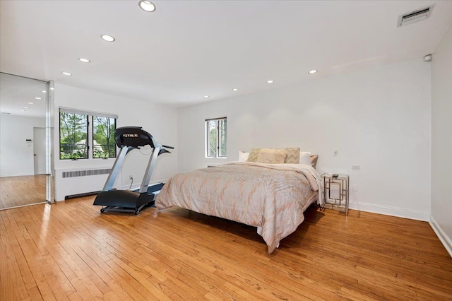 bedroom featuring radiator, multiple windows, light wood-style flooring, and recessed lighting