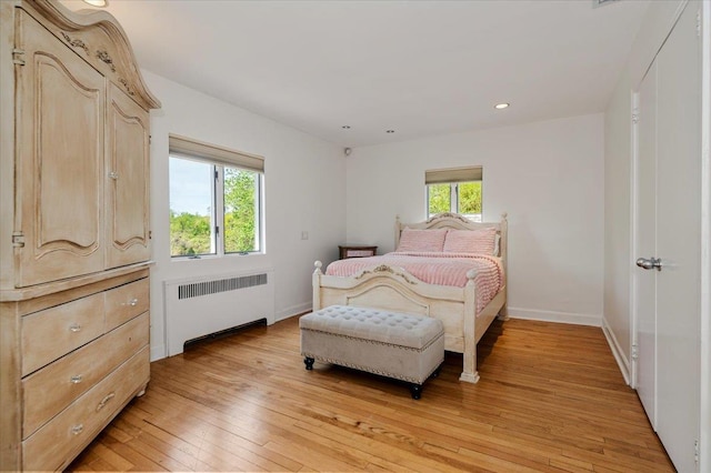 bedroom with radiator, light wood-style flooring, baseboards, and recessed lighting