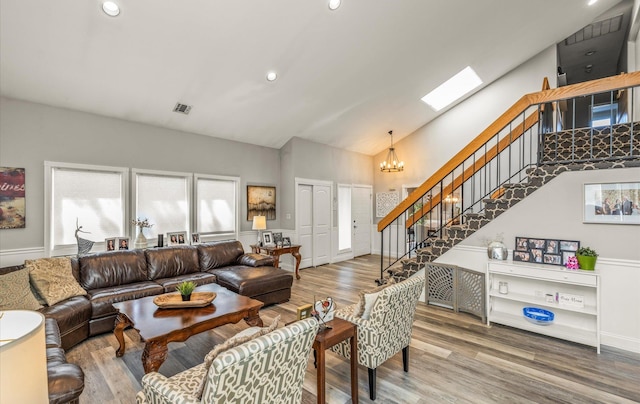 living area featuring stairway, a chandelier, high vaulted ceiling, and wood finished floors