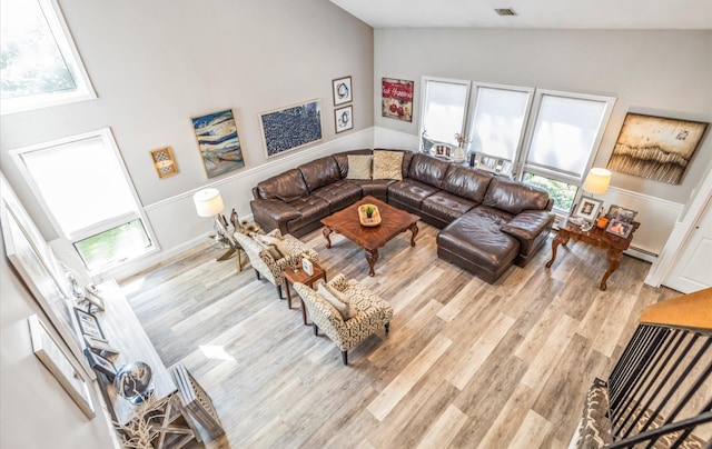 living room with a baseboard heating unit, wood finished floors, visible vents, and vaulted ceiling