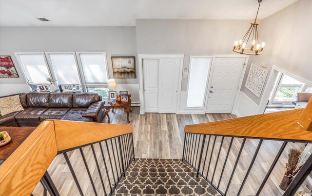 stairs with a notable chandelier, visible vents, and wood finished floors