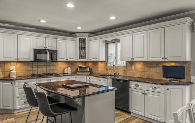 kitchen with a sink, light wood-type flooring, black appliances, and white cabinets