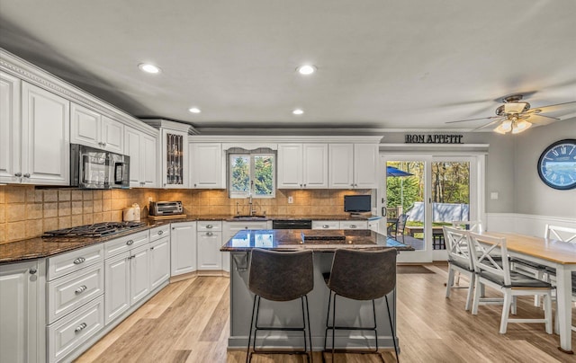 kitchen with black appliances, white cabinets, a sink, and a wealth of natural light
