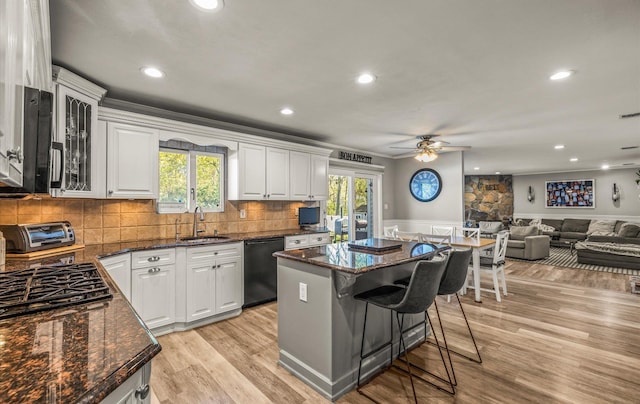 kitchen with a sink, black dishwasher, a ceiling fan, white cabinets, and a kitchen island