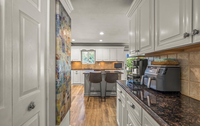 kitchen with backsplash, light wood-style floors, white cabinets, and a sink