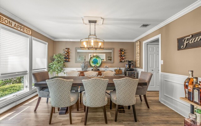 dining area featuring ornamental molding, a baseboard heating unit, visible vents, and wood finished floors