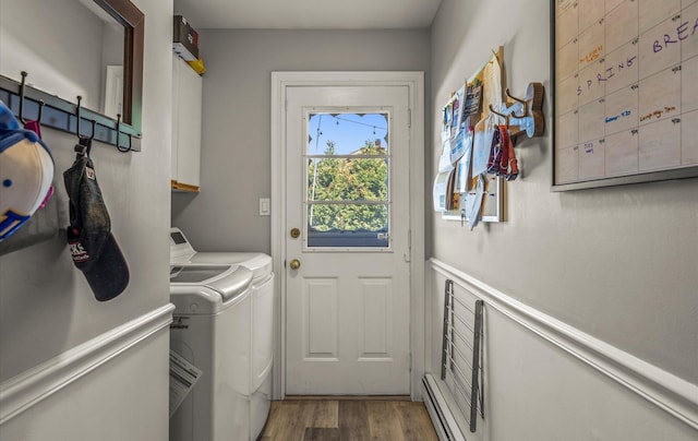 laundry area featuring a baseboard radiator, wood finished floors, cabinet space, and washer and clothes dryer