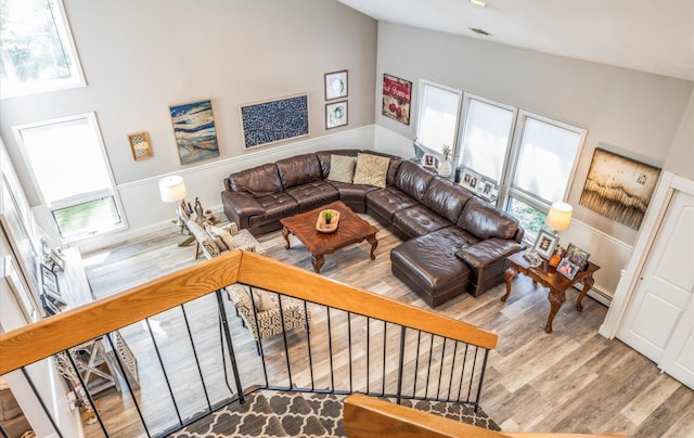 living room with vaulted ceiling, a baseboard radiator, a wealth of natural light, and wood finished floors