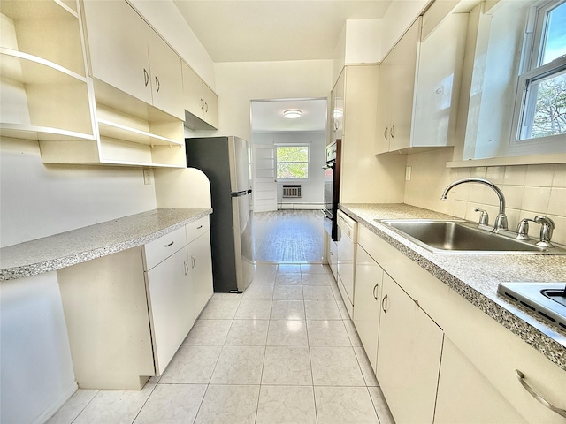 kitchen featuring freestanding refrigerator, black oven, light countertops, a sink, and dishwasher