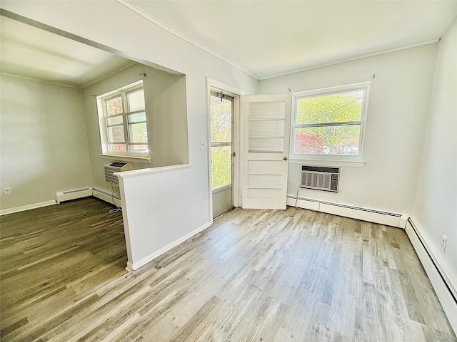unfurnished room featuring ornamental molding, wood finished floors, baseboard heating, and a wealth of natural light