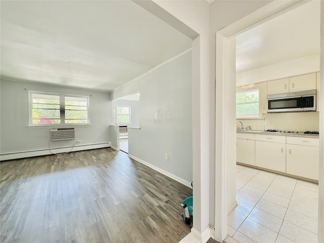 spare room with baseboards, a sink, light wood finished floors, and a wealth of natural light