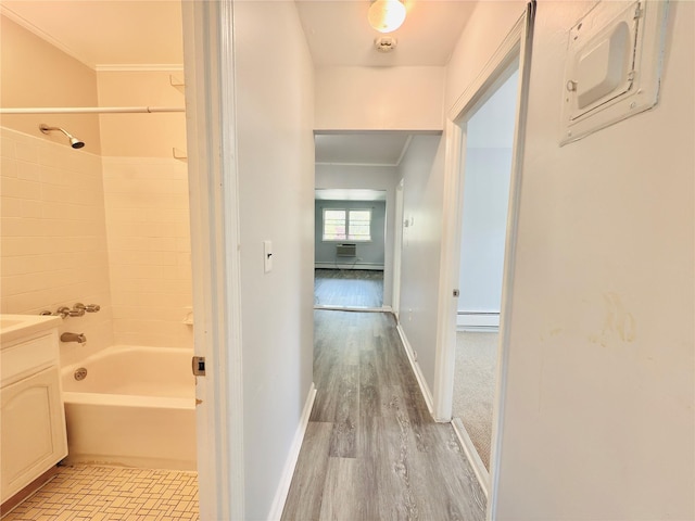 interior space with wood finished floors, baseboards, crown molding, and a baseboard heating unit