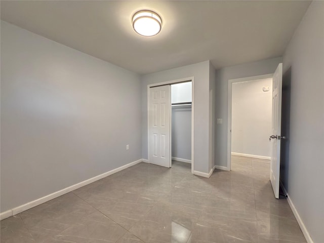 unfurnished bedroom with baseboards and a closet