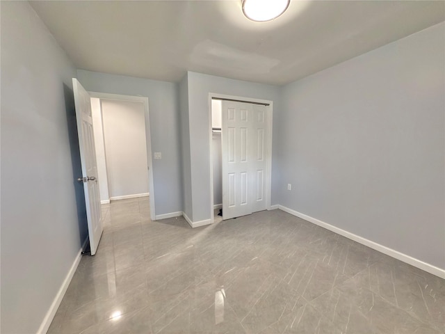unfurnished bedroom with baseboards and a closet