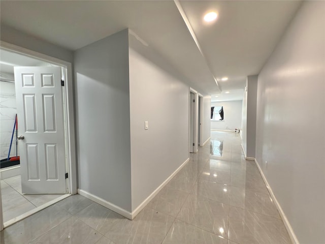 hallway with baseboards, recessed lighting, and marble finish floor