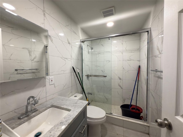 bathroom with visible vents, vanity, toilet, tile walls, and a marble finish shower